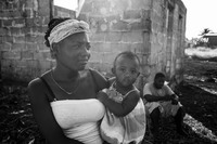 A women holding a friends child in a neighborhood in Belize City.