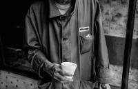 Still wearing his prison jacket only now with his name crossed out,  Earl stands underneath an abandoned storefront roof to stay dry.
